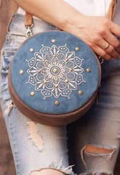 a woman is holding a blue purse with gold studded details on the front and sides