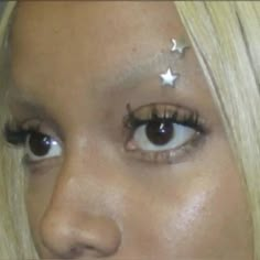 a close up of a woman with stars on her forehead and eyeliner, looking at the camera