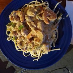 a blue plate topped with pasta and shrimp