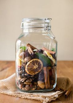 a glass jar filled with lots of different types of food and spices on top of a wooden table