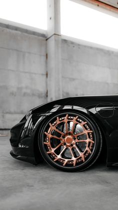 a black sports car with copper rims parked in a garage