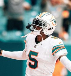 a football player wearing a white uniform and holding his arm out with one hand in the air