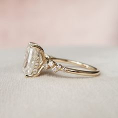 a close up view of a diamond ring on a white cloth with a pink background