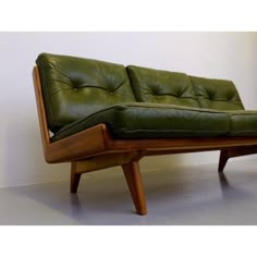 a green leather couch sitting on top of a wooden frame