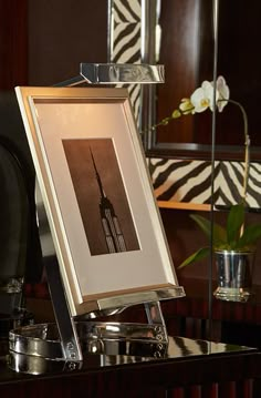 a framed photograph sitting on top of a table next to a vase with flowers in it