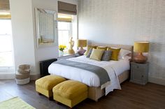 a bedroom with a large bed and yellow foot stools