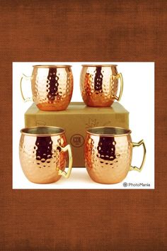 three copper mugs sitting on top of each other in front of a cardboard box