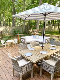 an outdoor table and chairs on a wooden deck with umbrellas over the dining area