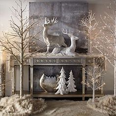 a fireplace decorated with white christmas decorations and deer figurines on it's mantle