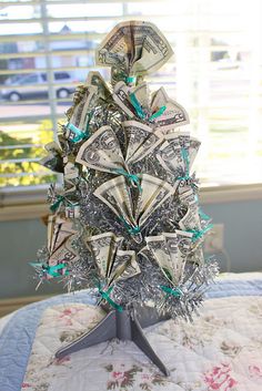 a christmas tree made out of money sitting on top of a table next to a window