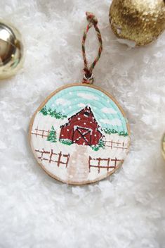 a christmas ornament with a red barn on it and other ornaments around it