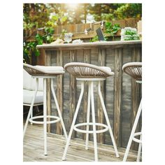 three white bar stools sitting next to a wooden table