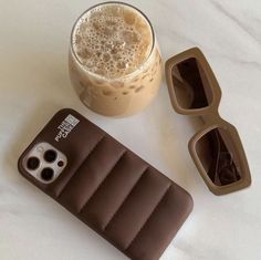 a cup of coffee next to an inflatable cell phone case with sunglasses on it