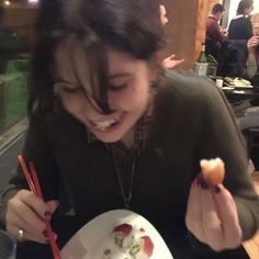 a woman eating sushi with chopsticks at a restaurant