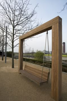 a wooden swing in the middle of a park