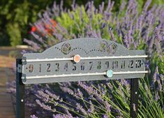 a metal sign with numbers and butterflies on it in front of some lavender flowers,