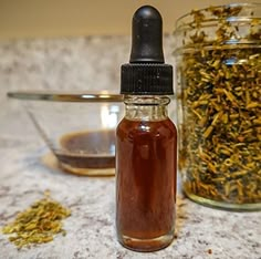 a glass bottle filled with liquid sitting on top of a counter next to a spoon