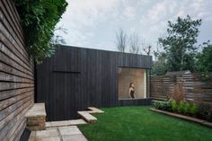 a woman is seen through the window of a modern house with grass and steps leading up to it