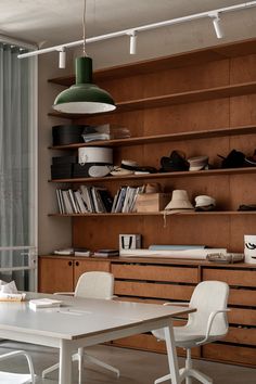 a dining room table with white chairs and bookshelves in front of the window