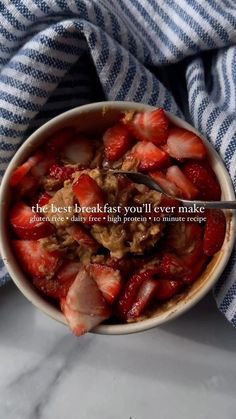 a bowl filled with strawberries sitting on top of a blue and white striped towel