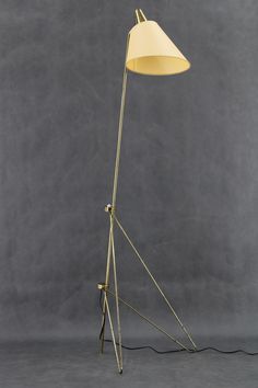 a floor lamp with a white shade on the top and a black base, against a gray background