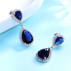 Add a splash of glamour to your look with these stunning earrings. You will love these luxurious and lustrous earrings. They are beautiful, elegant, and timeless. The sapphire (royalty stone) has been expertly set in sterling silver, at the center of a large teardrop-shaped rhodium plated drop which dangles with sparkle. This delicate piece makes an ideal gift that combines looks with a unique outlook on life! Our beautiful, bejeweled earrings are designed to dazzle. You will love the dainty sap White Gold Sapphire, Silver Jewelry Fashion, Swarovski Crystal Earrings, Drop Dangle Earrings, Stunning Earrings, White Sapphire, Teardrop Earrings, Crystal Earrings, Rhodium Plated