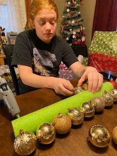 a woman is decorating christmas ornaments on a table