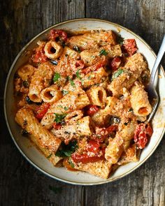 a bowl filled with pasta and sauce on top of a wooden table