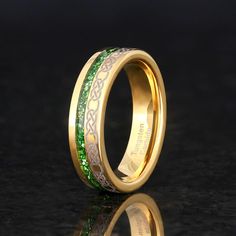 a gold ring with green and white enamel inlays on the inside of it