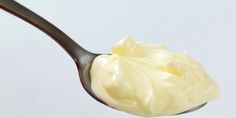 a spoon filled with cream on top of a white table