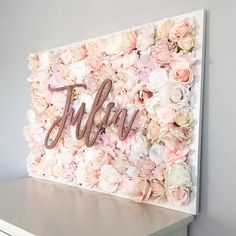 a flower wall with the word hello spelled in cursive font on it and flowers