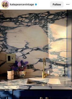 a kitchen with marble counter tops and gold faucets on the sink, next to a blue cabinet