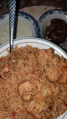 a white plate topped with rice and meat next to other plates filled with food on top of a table