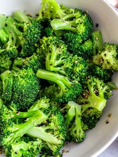 a white bowl filled with broccoli on top of a table