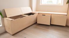 an empty wooden box sitting on top of a hard wood floor next to a window