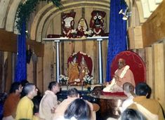 a group of people sitting in front of a stage with an idol on the wall