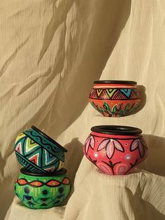 three painted pots sitting on top of a white sheet