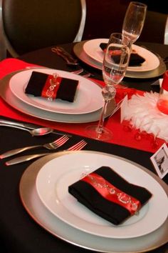 the table is set with black and red place settings