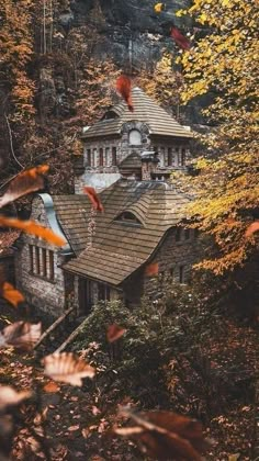 an old house in the woods surrounded by fall leaves