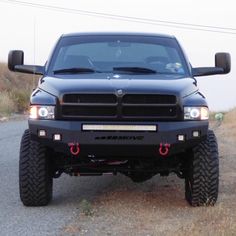 a black truck parked on the side of a road next to a grass covered field