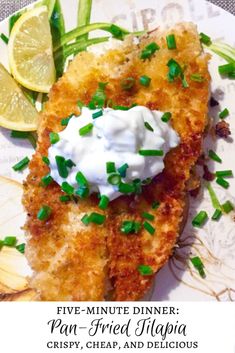 a white plate topped with fried fish covered in sour cream