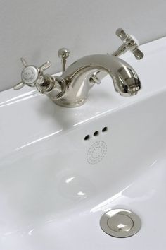 a white sink with chrome faucet and soap dispenser