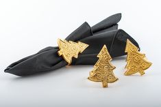 three gold christmas trees sitting on top of black napkins next to each other and one has an ornament in the shape of a tree