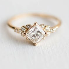 a gold ring with a princess cut diamond surrounded by small diamonds