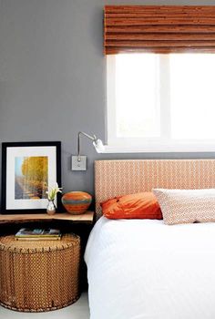 a bed sitting under a window next to a basket on top of a wooden table