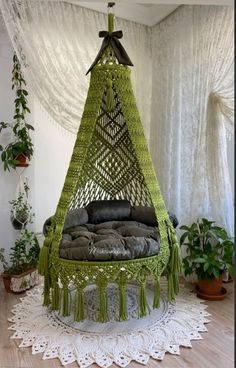 a green hammock hanging from the ceiling in a room with potted plants