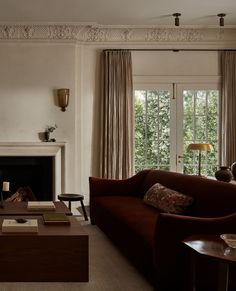 a living room filled with furniture and a fire place in front of a large window