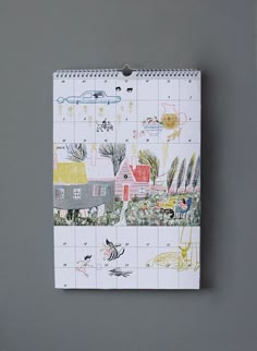 a calendar with an image of houses and animals on the cover is hanging on a wall