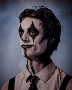 a man with his face painted as the joker is wearing suspenders and a tie