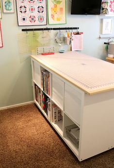 a room with a desk, bookshelf and various pictures on the wall above it